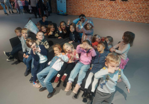 Zdjęcie przedstawia grupę dzieci oczekujących na spektakl