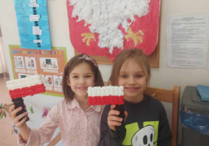 Zdjęcie przedstawia dzieci, które z klocków ułożyły flagi Polski a w tle widać godło Polski, które wykonała gupa