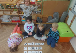 Zdjęcie przedstawia grupę dzieci, która z rozsypanki literowej ułożyła wyrazy