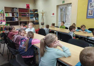 Na zdjęciu widzimy grupkę dzieci, które słuchają i odpowiadają na pytania dotyczące jesieni.