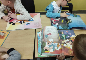 Na zdjęciu widzimy trójkę chłopców, którzy oglądają książki.