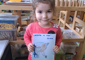 Zdjęcie przedstawia dziewczynkę trzymającą zrobioną przez siebie książkę.