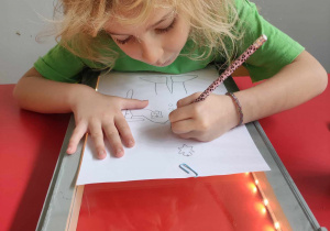 Dziewczynka kalkuje obrazek na specjalnej tablicy