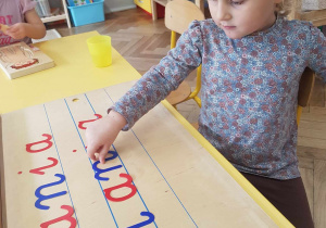 Dziewczynka układa swoje imię z ruchomego alfabetu