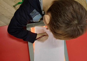 Chłopiec kalkuje obrazek na specjalnej tablicy