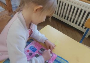 Na zdjęciu widać dziewczynkę która rysuje swój dom