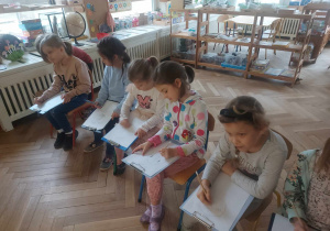 Zdjęcie przedstawia grupę dzieci, które szkicują portret Janusza Korczaka