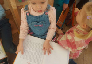 na zdjęciu widać dziewczynkę, która ogląda książkę o Prawach Dziecka autorstwa Pana Marka Michalaka