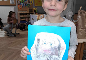 Zdjęcie przedstawia chłopca trzymającego w ręku narysowany przez siebie portret Janusza Korczaka.