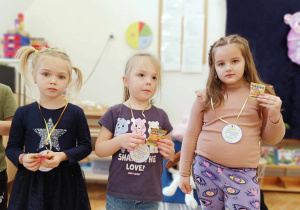 Dzieci stoją i pokazują medale i słodki poczęstunek.