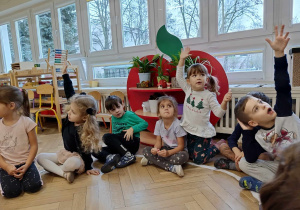 Dzieci siedzą na podłodze i zgłaszają się do wykonania kolejnego zadania.