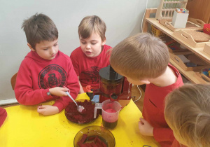 Na zdjęciu widzimy chłopców, którzy tworzą sok buraczany. Jeden z chłopców zgarnia nią pulpę, która tworzy się podczas produkcji soku.