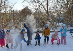 Grupa dzieci rzuca śnieżkami.