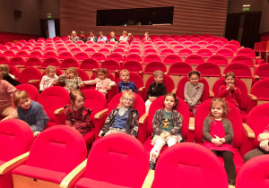 Zdjęcie przedstawia dzieci siedzące w teatrze.