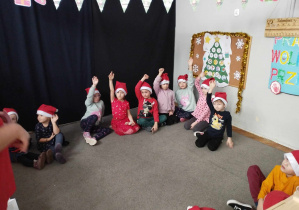 Na zdjęciu widzimy grupkę dzieci, które podnoszą ręce, aby powiedzieć, że m.in.: upiekły już pierniki.