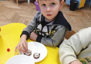 Zdjęcie przedstawia jak chłopiec dekoruje pierniki.