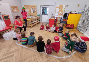 Dzieci skupione wokół pomocników Mikołaja w klasie.