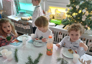 Dzieci siedzą przy stole jedząc potrawy Wigilijne