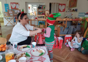 Pomocnik Mikołaja wręczający prezenty dzieciom.