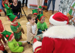 Dzieci odbierające prezenty od Mikołaja.