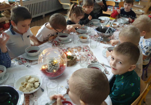 Na zdjęciu widzimy grupkę dzieci, które jedzą barszcz czerwony.