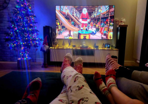Zdjęcie przedstawia stopy rodziny oglądającej bożonarodzeniowy film.