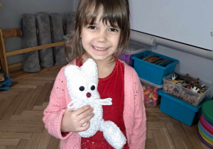 Zdjęcie przedstawia dziewczynkę ze swoją zabawką zrobioną przez rodziców.