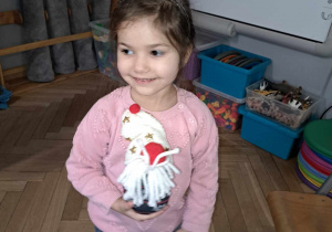 Zdjęcie przedstawia dziewczynkę ze swoją zabawką zrobioną przez rodziców.