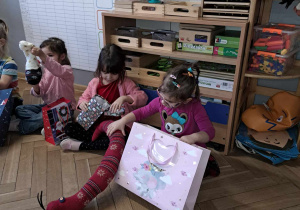 Zdjęcie przedstawia dzieci rozpakowujące swoje zabawki.