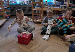 Zdjęcie przedstawia dzieci rozpakowujące swoje zabawki.