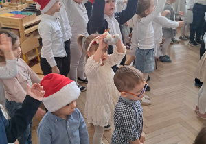 Zdjęcie przedstawia dzieci śpiewające kolędę i unoszące ręce do góry.