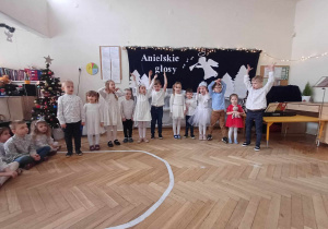 Na zdjęciu widzimy dzieci z grupy I, które śpiewają fragment kolędy "Gloria in excelsis Deo" i mają uniesiąne ręce do góry.