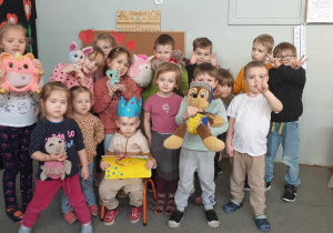 Zdjęcie przedstawia grupę dzieci z maskotkami, pozującą do zdjęcia.