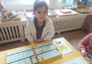 Zdjęcie przedstawia dziewczynkę, która z wykorzystaniem klocków Rocławskiego układa i odczytuje wyrazy