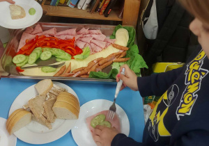 Zdjecie przedstawia dzieci, które dokonują wyboru co będą jadły i komponują swoją kanapkę.