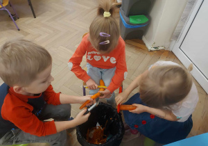Zdjęcie przedstawia dzieci obierające marchewki na ciasto