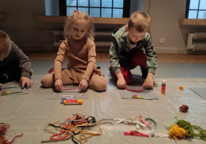 Zdjęcie przedstawia dzieci wykonujące prace z różnorodnych materiałów typu sznurki, tasiemki.