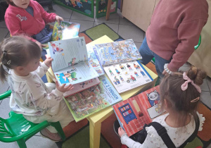 Zdjęcie przedstawia dziewczynki oglądające książki.
