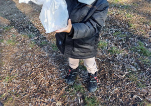 Zdjęcie przedstawia chłopca łapiącego powietrze w torebkę.