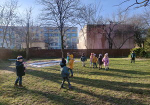 Zdjęcie przedstawia dzieci znajdujące się w ogrodzie. Dwoje z nich puszcza bańki mydlane.