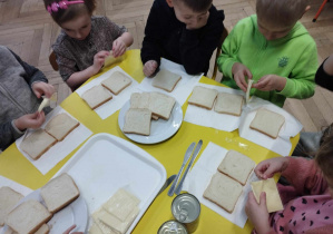 Na zdjęciu widzimy dzieci, które otwierają zawinięty w folię ser tostowy.