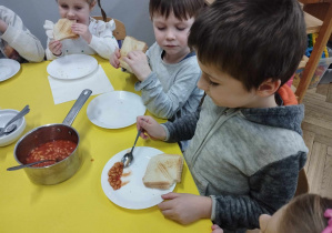 Na zdjęciu widzimy chłopca, który degustuje fasolki w pomidorach.