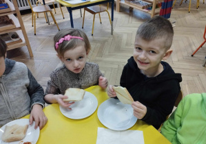 Na zdjęciu widzimy chłopca i dziewczynkę, którzy zajadają się tostami.