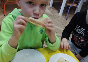 Na zdjęciu widzimy chłopca, który zjada tosta.