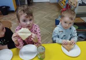 Na zdjęciu widzimy dwójkę dzieci, które jedzą tosty.