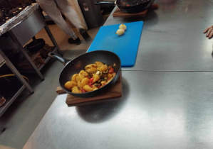 Na zdjęciu widzimy patelnię, na której znajduje się makaron podobny do muszki ślimaka z grliowanymi warzywami.
