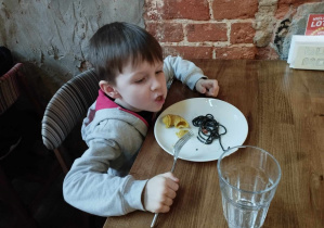 Na zdjęciu widzimy chłopca, który próbuje czarnego makaronu oraz makaronu w kształcie ślimaka.