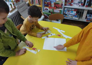 Na zdjęciu widzimy dzieci, które układają puzzle z ilustracjami przedstawiającymi Kubusia Puchatka i jego przyjaciół.