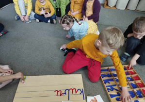 Na zdjęciu widzimy chłopca, który układa napis "Kubuś Puchatek" z wykorzystaniem ruchomego alfabetu.