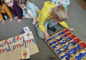 Na zdjęciu widzimy chłopca, który układa napis "Prosiaczek" z wykorzystaniem ruchomego alfabetu.